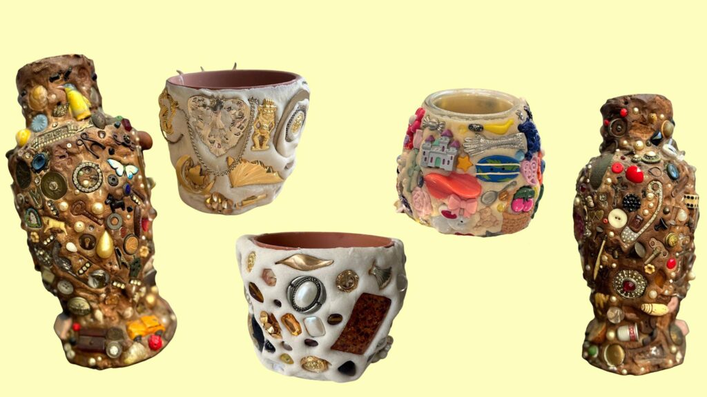 Conjunto de cinco piezas decorativas artesanales sobre un fondo amarillo claro. Dos piezas a los extremos son jarrones de estilo rústico, de color marrón oscuro, densamente decorados con una gran variedad de objetos pequeños, como botones, cuentas, juguetes miniatura y abalorios. En el centro, dos macetas o cuencos más pequeños: dos con una base de color blanco crema decorados con joyería dorada y elementos metálicos, y otro con una base blanca adornada con una colorida colección de accesorios, incluyendo una figura de un castillo, flores, una cereza y otros objetos decorativos.